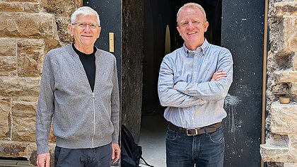 Bernhard Bayer und Frank Metzger stehen vor dem Durchbruch von der Kirche Mariä Himmelfahrt zum Friedhof