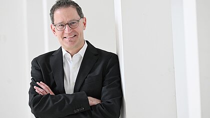 Zu sehen ist der stellvertretende Stadtdekan Michael Heil, der an einer Säule lehnt.