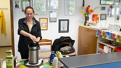 Diana schenkt Kaffee aus und lächelt dabei 