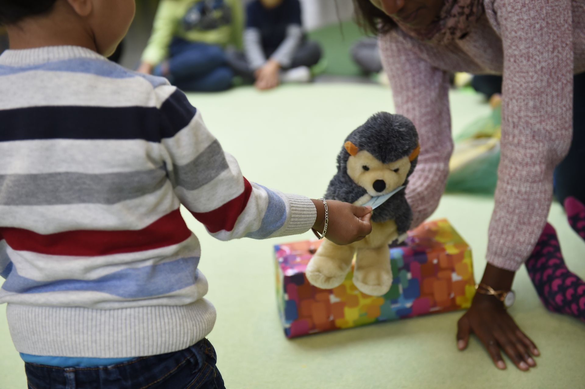 Kind und Erzieherin spielen in dem Kinder- und Familienzentrum St. Georg mit einem Stoffigel.