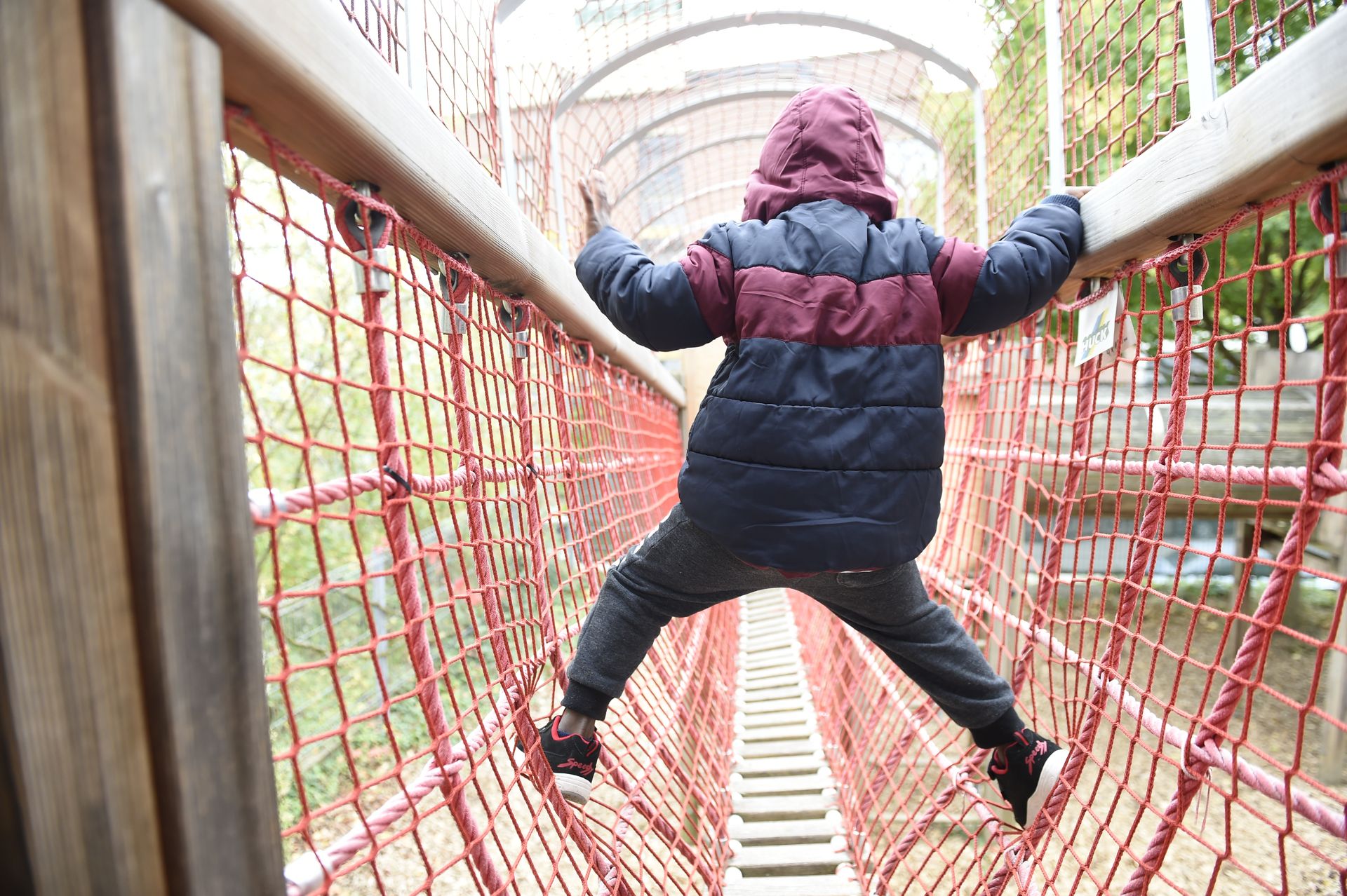 Junge klettert geschickt über ein gespanntes Netz, das im Garten des katholischen Kinder- und Familienzentrums St. Georg steht. 